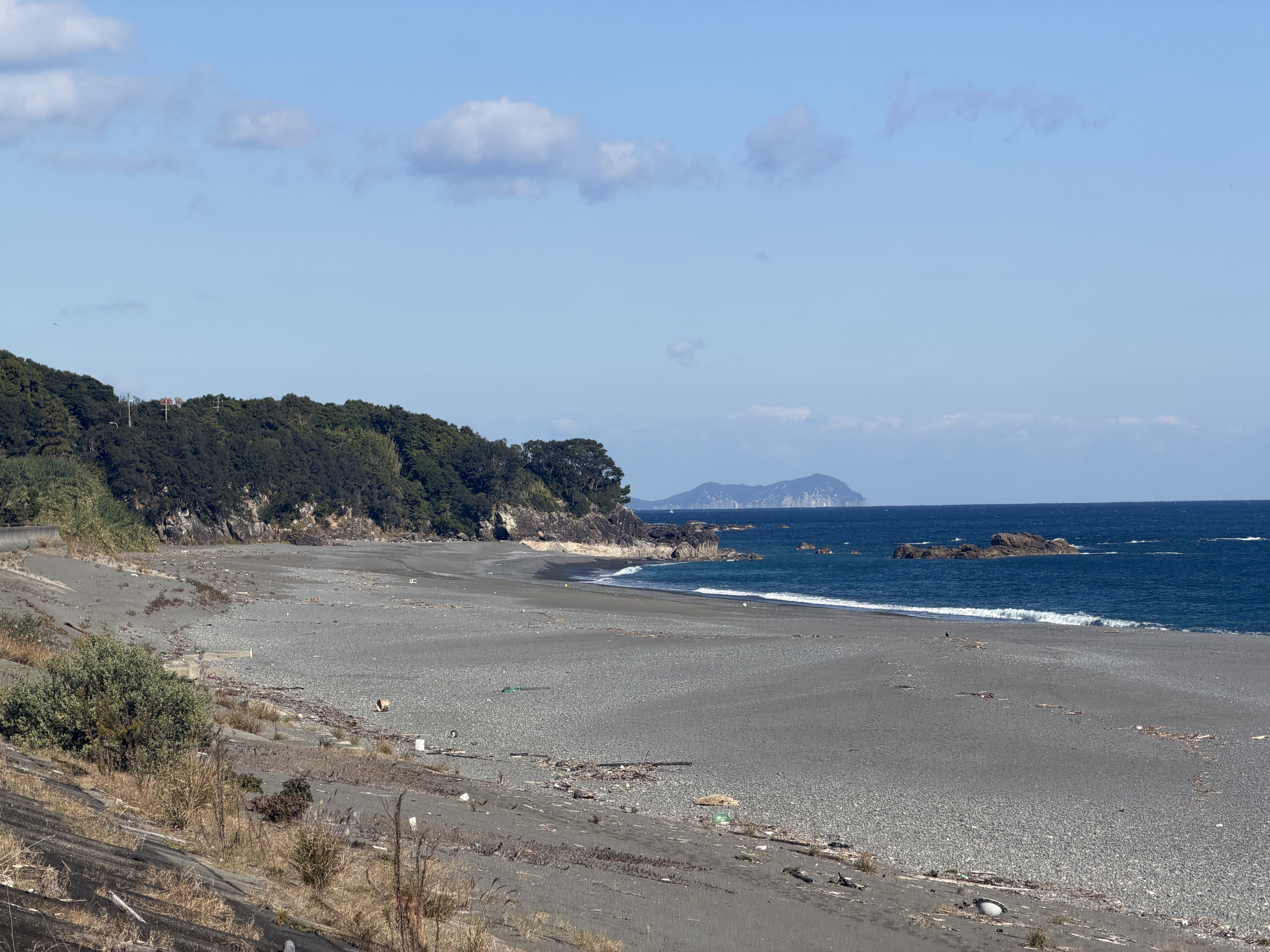 Wide pebble beach meeting the blue Pacific ocean
